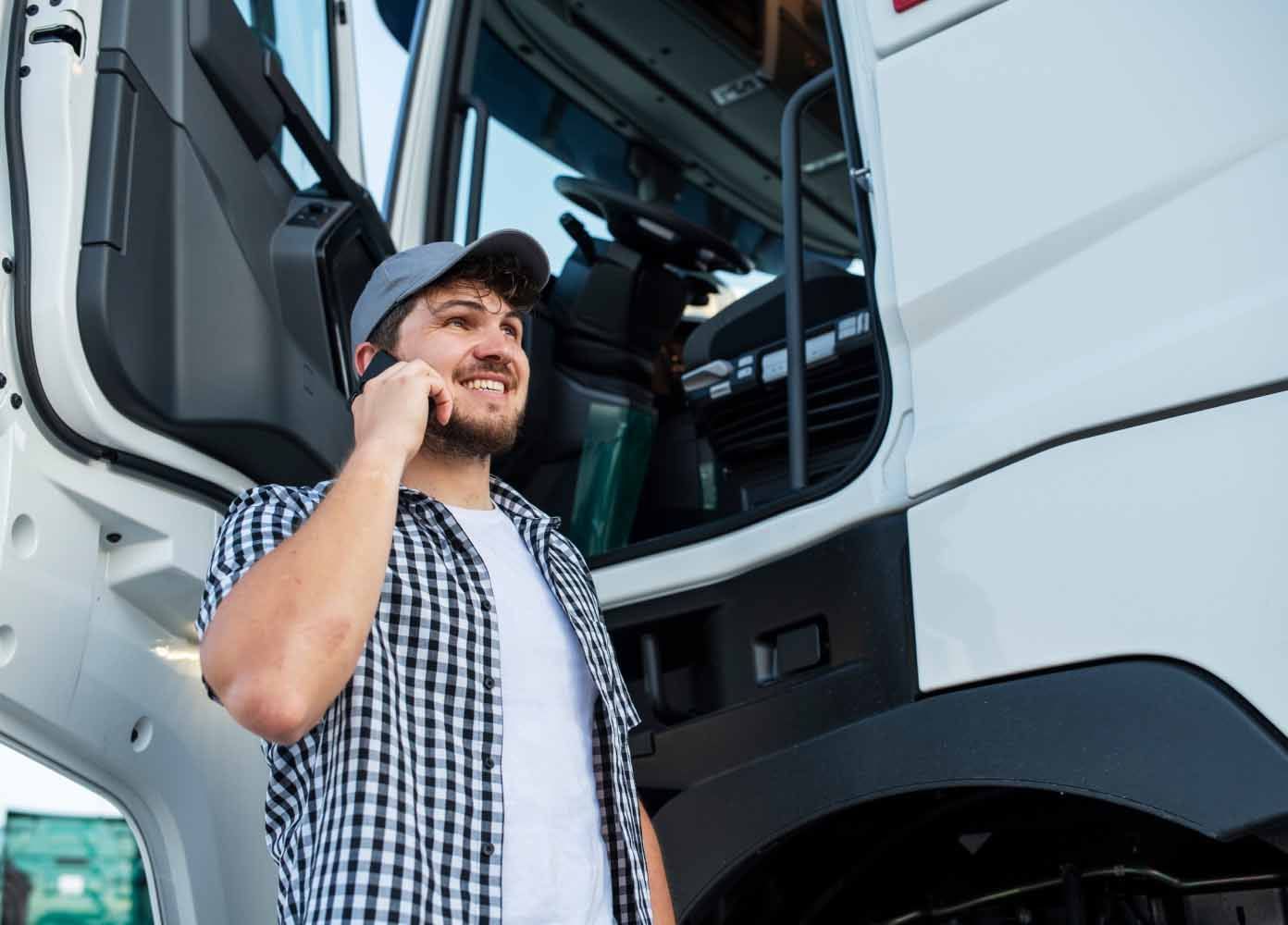 A ZMac carrier stands outside his truck with the door open. He is smiling and speaking on his phone.