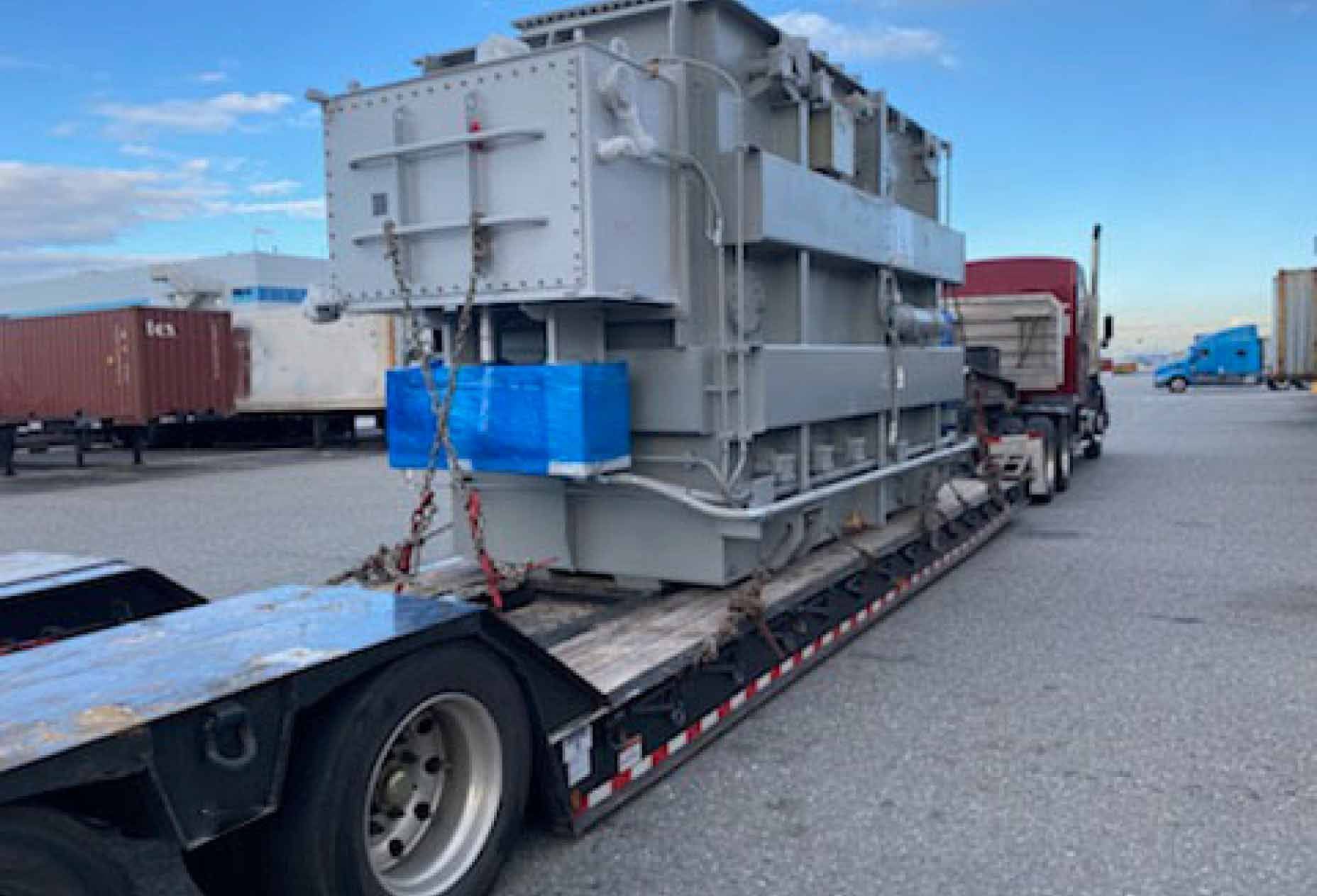 Close look at a load strapped down to a truck's low bed.